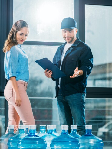 courier-with-clipboard-and-woman-looking-at-delivered-water-bottles.jpg